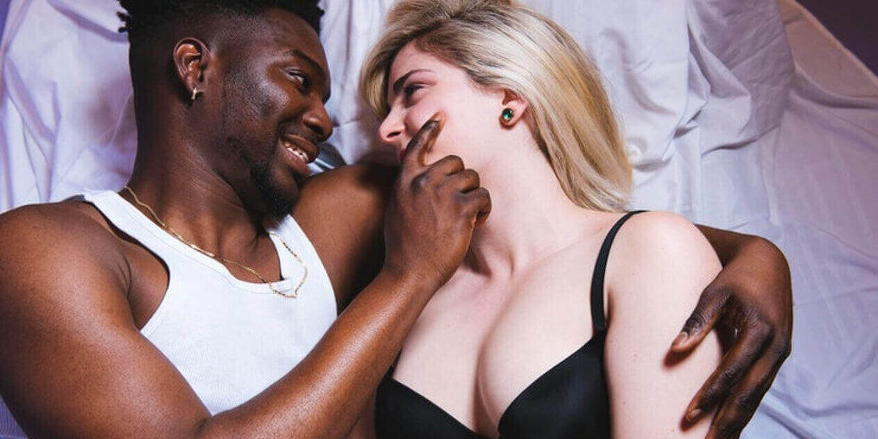 A Black man and a white woman cuddling affectionately